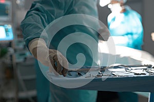 Midsection of biracial male surgeon holding instruments in operating theatre at hospital