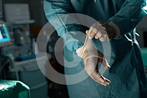 Midsection of biracial male surgeon wearing surgical gown and gloves in operating theatre