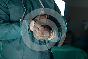 Midsection of biracial male surgeon wearing surgical gown in operating theatre at hospital