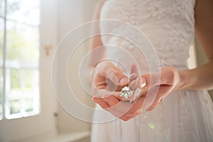 Midsection of bride holding diamond earring at home