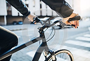 A midsection of businessman commuter with electric bicycle traveling to work in city.