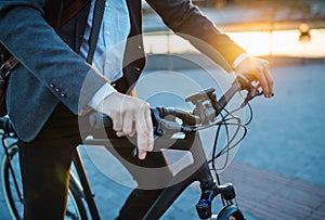 Midsection of businessman commuter with electric bicycle traveling from work in city.