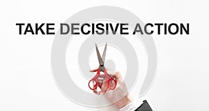 Midsection of businessman cutting the word TAKE DECISIVE ACTION on paper with scissors over gray background