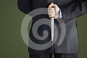 Midsection Of Businessman Holding Knife Behind Back