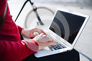 A midsection of businessman sitting on bench in city, using laptop. Copy space.