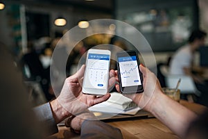 Midsection of businesspeople having business meeting in a cafe, using smartphones.