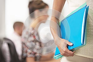 Midsection Of Businesswoman Carrying Folder With Colleagues Behind