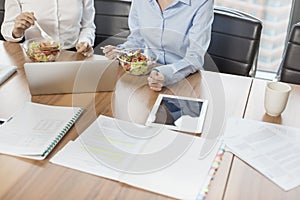 Midsection of businesswomen eating lunch while sitting at table in boardroom