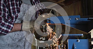 Midsection of caucasian male knife maker in workshop using angle grinder