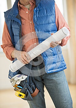 Midsection Of Construction Worker Holding Blueprint
