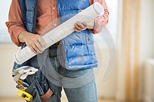 Midsection Of Construction Worker Holding Blueprint