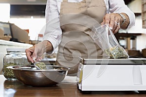 Midsection of an employee measuring ingredient on weight scale in spice store