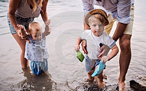 A midsection of family with two toddler children outdoors by the river in summer.