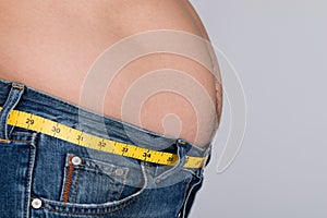 Midsection of fat man with measure tape around waist