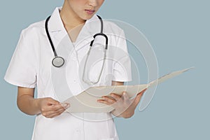 Midsection of a female doctor reading medical report over light blue background