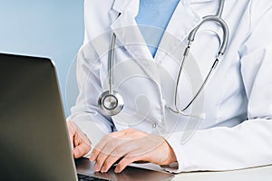 midsection of female doctor using her laptop in the office.