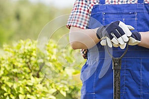 Midsection of gardener holding spade in plant nursery