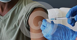 Midsection of gloved female doctor giving vaccination to senior african american man