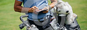 Midsection of golfer writing on score card standing at golf course