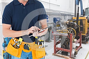 Midsection of handyman using tablet PC at workshop