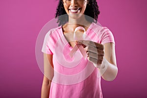 Midsection of happy african american mid adult woman holding pink breast cancer awareness ribbon
