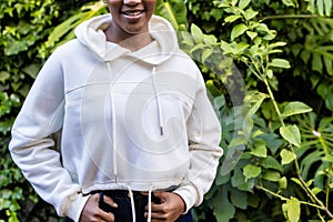 Midsection of happy african american woman wearing white hooded sweatshirt standing in garden