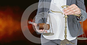 Midsection of judge holding law scales and hammer