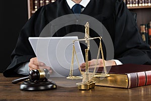 Judge Reading Documents At Desk In Courtroom