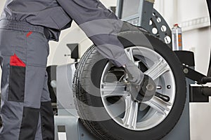 Midsection of male mechanic repairing car's wheel in repair shop