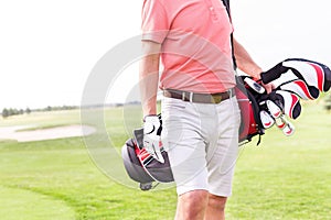 Midsection of man with golf club bag standing at course