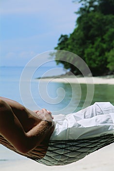 Midsection of man lying in hammock at beach