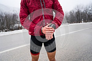 Midsection of man standing outdoor in winter day checking his smart wristwatch for time and hart-rate while training outdoor male