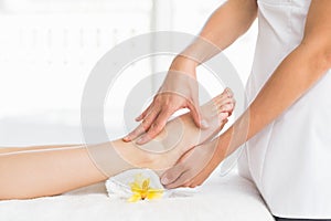 Midsection of masseur giving foot massage to woman