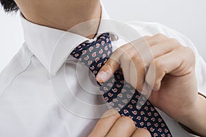 Midsection of mid adult businessman adjusting tie