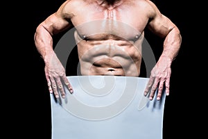 Midsection of muscular man holding white blank paper