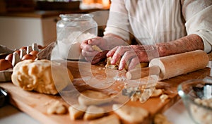 Midsection of old woman making cakes in a kitchen at home.