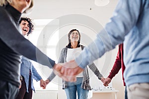 Midsection of people standing in a circle and holding hands during group therapy.