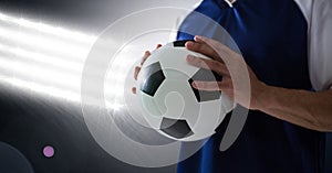 Midsection of player holding soccer ball