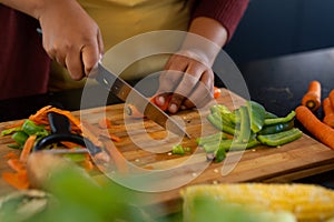 Midsection of plus size african american woman preparing dinner, chopping vegetables in kitchen