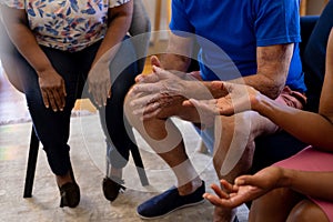 Midsection of senior diverse people sitting on chairs and talking in group therapy session