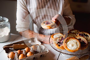 A midsection of senior grandmother making and holding cakes at home.