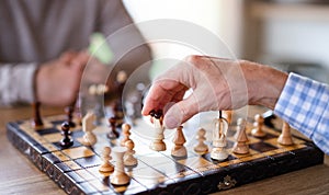 Midsection of senior men friends at home, playing chess.