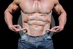 Midsection of shirtless man pointing at abs