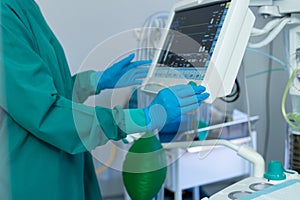 Midsection of surgeon's gloved hands operating computerised medical equipment in operating theatre