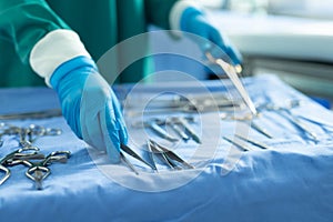 Midsection of surgical tech placing surgical tools on table in operating theatre