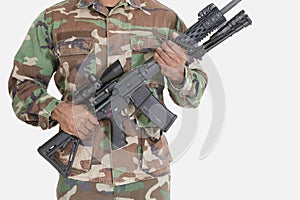 Midsection of US Marine Corps soldier holding M4 assault rifle over gray background