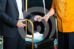 Midsection view of man giving tip in hotel