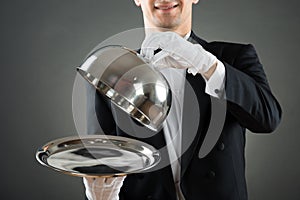 Midsection Of Waiter Holding Cloche Over Empty Tray