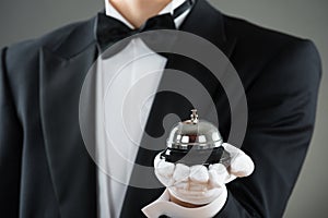 Midsection Of Waiter Holding Service Bell