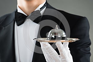 Midsection Of Waiter Holding Service Bell In Plate